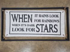 A large canvas and metal sign 'When it Rains Look for Rainbows, When it's Dark,