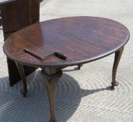 A c1930's oval wind out extending dining table raised over plain Queen Anne style legs,