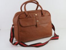 A tan coloured overnight bag having canv