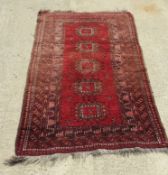 A woollen rug in red, measuring approx 167 x 99cm.