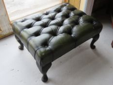 A green leatherette Chesterfield type footstool raised over cabriole legs.