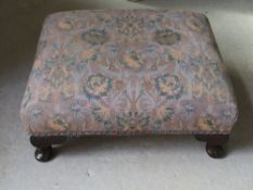 A low footstool upholstered in Liberty type patterned fabric, measuring approx 49 x 43 x 20cm.