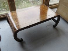 An Oriental style coffee table raised over carved scrolling feet. Measuring approx 100 x 52 x 34.
