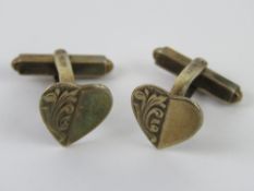 A pair of silver heart shaped cufflinks.