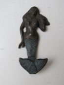 A cast metal hook in the form of a mermaid.
