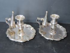 A pair of silver plated chamber sticks, each with snuffer and having emblem upon.