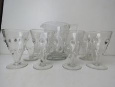 A clear glass lemonade set comprising six goblets and jugs.