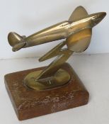 A desktop model of a Spitfire on lightening bolt stand raised over wooden base,