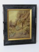 An Ernest Walbourn print under perspex featuring girl sat at an open door of cottage.