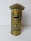 A brass money box in the form of a postbox, having VR cypher to front and standing 17cm high.