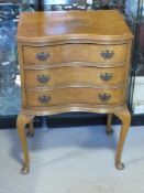 A bow fronted collector's cabinet having three drawers raised over Queen Ann style legs with brass