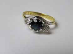 A sapphire and diamond 18ct gold and platinum ring, the central sapphire of dark blue hue,