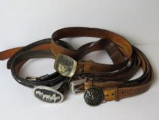 A quantity of assorted men's leather belts having various buckles upon, inc stag, ducks, etc,