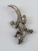 A pendant in the form of a ghekko having three articulated panels and measuring 3.5cm in length.