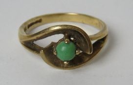 A 9ct gold ring having central green cabachon in wraparound setting, size O, 2.8g.
