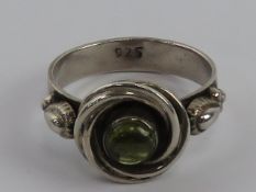 A silver and green stone ring having central cabachon with wreath design, stamped 925, size R.