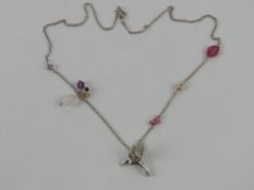 A silver necklace having hummingbird pendant, pearl, crystal and floral decoration upon,