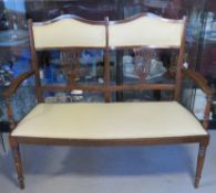 A reproduction Edwardian style two seater hall or salon chair upholstered in cream and having leaf