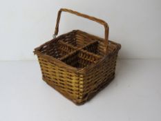 A wicker basket to hold four bottles, having swing handle over, approx 24cm wide.