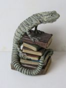 A Jill Moger sculpture of a lizard on a stack of books, standing 26.5cm high.
