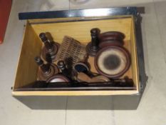 A black painted trunk opening to reveal a quantity of turned wooden items including candlesticks.