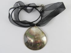 A mother of pearl pendant on ribbon neck
