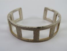 An HM silver bangle having open square s