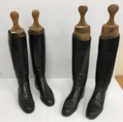 Two pairs of black hunting boots with wooden trees