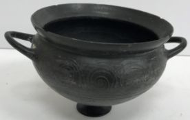 An Etruscan black glazed terracotta bowl with two side handles, raised on a small circular foot 12.