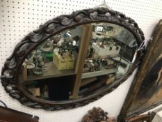 A 20th Century carved oak framed oval wall mirror in the Rococo taste with bevel edge plate 104 cm