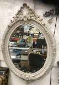 A 20th Century faux marble framed oval wall mirror in the Georgian style with scrolling foliate and