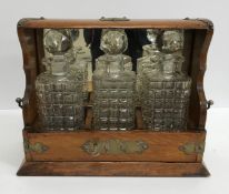 A late Victorian oak tantalus with brass Gothic style mounts (formerly plated) containing two