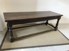 An 18th Century oak refectory style dining table, the three plank top above a lunette carved frieze,
