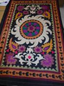 A 20th Century Middle Eastern table cover with stylised foliate decoration on a black ground 131 cm