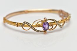 A YELLOW METAL AMETHYST AND SEED PEARL BANGLE, hollow hinged yellow metal knife edge bangle,