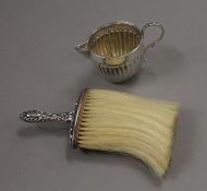 A small silver cream jug (53 grammes) and a silver handled crumb brush. The former 6.5 cm high.