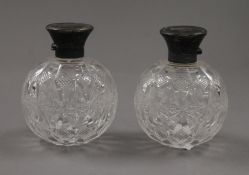 A pair of silver topped cut glass scent bottles. 10 cm high.