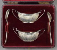 A cased pair of silver salts with one silver spoon and one plated spoon. 36.4 grammes.