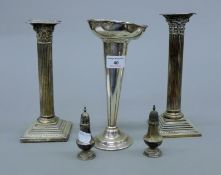 A pair of silver candlesticks, two silver peppers and a plated vase. The former 23 cm high.