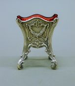 A silver salt with cranberry glass liner, hallmarked for London 1901, maker's mark Wm Comyns & Son.