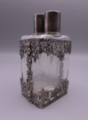 A pair of glass scent bottles housed in a pierced unmarked silver mount. 10.5 cm high.