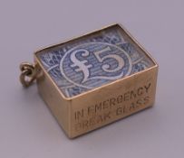 A 9 ct gold charm with enclosed bank note. 1 cm high. 3 grammes total weight.