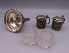 A pair of silver mustard pots, a silver wine funnel and a pair of glass salts.