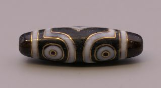 A gold inlaid dzi bead. 4 cm long.