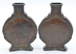 A pair of Japanese Meiji period bronze moon flasks decorated to both sides with performing circus