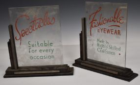 Two Art Deco style optician's shop display signs, one advertising spectacles suitable for all