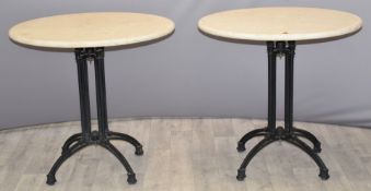 Pair of circular cream marble tables raised on iron column supports with outswept legs and hoof