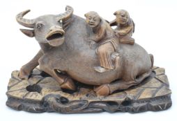 Chinese carved wooden water buffalo with figural riders and glass eyes, on carved wooden stand, 34cm