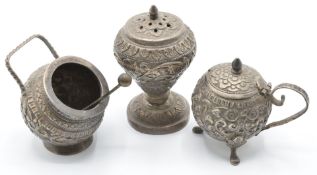 Indian or Burmese silver cruet items with embossed decoration comprising pepper, salt and mustard,