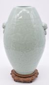 Chinese celadon vase with moulded decoration and stylised ring handles, on carved wooden stand,